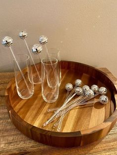 four glasses and five silver balls on a wooden tray