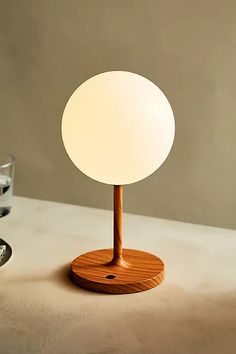 a table lamp sitting on top of a counter next to a glass filled with water