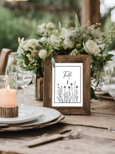 the table is set with white flowers, candles and place cards for guests to sign