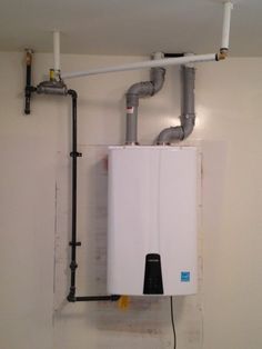 a water heater mounted to the side of a wall with pipes running from it