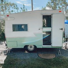 an old camper trailer is parked in the grass