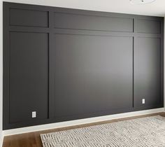 an empty room with dark gray walls and white trim on the wall, along with a rug