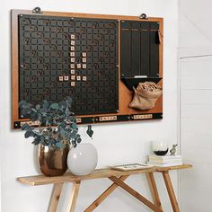 a wooden table topped with a vase filled with flowers next to a wall mounted scrabble board