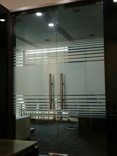 an empty room with glass doors and benches in it's center area, as seen from the outside