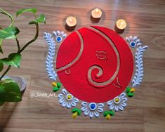 a decorated red and white mat with candles on it next to a potted plant