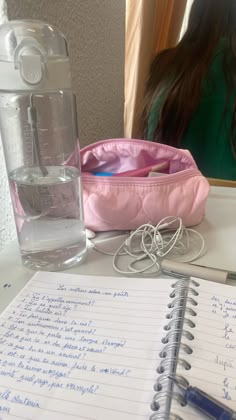 a notepad with writing on it next to a water bottle and a glass filled with water