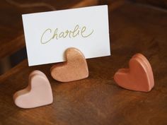 three heart shaped magnets sitting on top of a wooden table next to a card