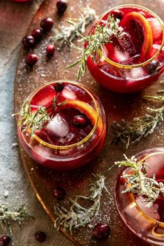 two glasses filled with red liquid and garnished with herbs on a wooden tray