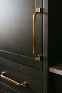 a close up of a door handle on a black cabinet with gold handles and drawers