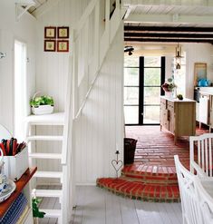 an open kitchen and dining area with stairs leading to the upper floor, white painted walls