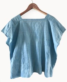 a blue top hanging on a wooden hanger