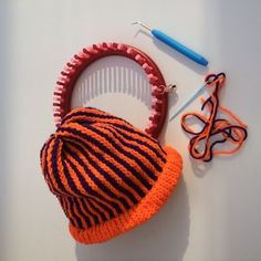 an orange and black knitted hat sitting on top of a table next to a pair of scissors