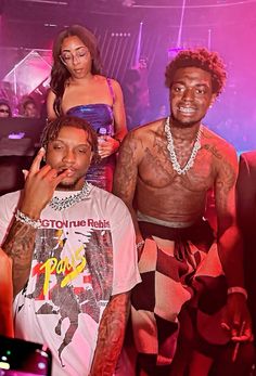 two men and one woman posing for the camera in front of a crowd at a nightclub