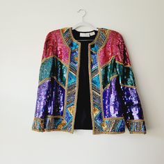 Vintage Laurence Kazar Sequined holiday bolero jacket featuring bright colorblocked panels of pink, purple, and teal green, with patterned and beaded trim and hems.  100% silk, with rayon lining and built-in shoulder pads. Hook and eye closures up the front. Made in India. Heavy from the weight of the beads and sequins. Tag reads size medium.  Shoulder to shoulder: 15 inches.  Across the bust: 19.5 inches.  Top of shoulder to bottom hem: 23 inches.  Sleeve to shoulder: 20 inches.  Check out othe Multicolor Embellished Outerwear For Winter, Embellished Multicolor Party Outerwear, Multicolor Embellished Party Outerwear, Festive Multicolor Embellished Outerwear, Fantastic Fashion, Wedding Shrug, Shrugs And Boleros, Purple And Teal, Evening Jacket