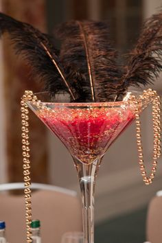 a tall wine glass filled with liquid and feathers