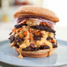 a cheeseburger with onion, lettuce and onions on a blue plate