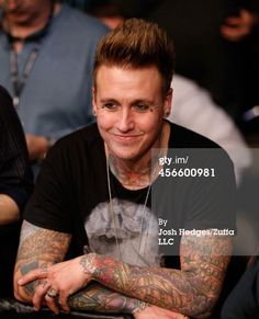 a man with tattoos sitting in front of other people