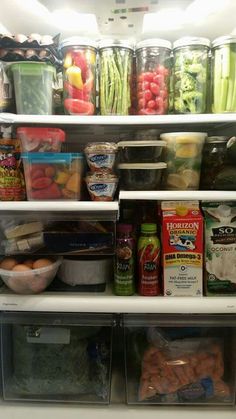 an open refrigerator filled with lots of food and containers full of vegetables, fruits and other items