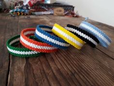 four different colored bracelets sitting on top of a wooden table next to each other