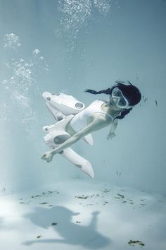 a woman floating in the water next to a white jetliner under water with bubbles