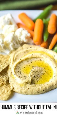 hummus recipe without tahini on a white plate with carrots and crackers