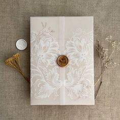 a card with a button on it next to some dried flowers and a small coin