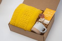 a yellow knitted blanket and coffee mug in a box