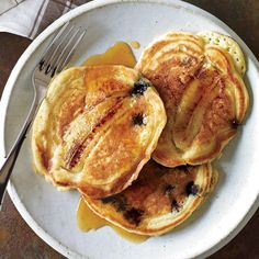 three pancakes on a plate with syrup drizzled over them and two forks