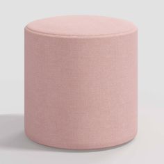 a light pink round ottoman sitting on top of a white floor next to a wall