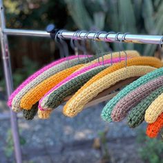 multicolored crocheted scarves hanging from a clothes line in front of cacti