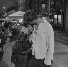 a man and woman standing next to each other on a street corner at night time