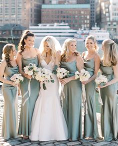 a group of women standing next to each other in front of a body of water