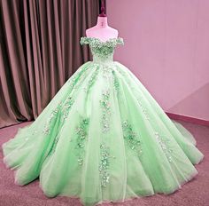 a green ball gown is on display in front of a pink wall and drapes