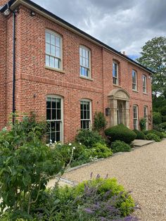 a large brick building with lots of plants and flowers around it's perimeters