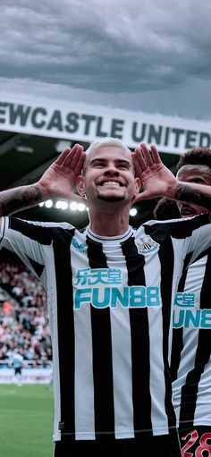 two men in black and white shirts standing on a soccer field with their hands up