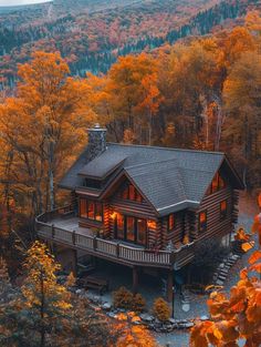 an aerial view of a log cabin surrounded by fall foliage and trees in the background