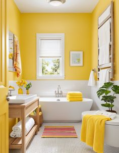 a bathroom with yellow walls and white bathtub next to a sink, toilet and window