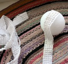 a close up of a white object on a multicolored knitted rug with crochet edging