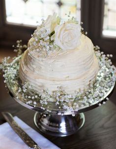 a wedding cake with white flowers and baby's breath on the top is ready to be cut