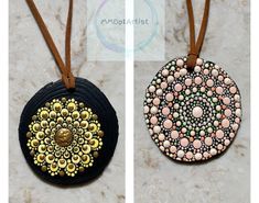 two circular pendants with beaded designs on brown leather cord hanging from marble counter top