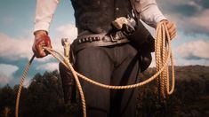 a man holding two ropes in one hand and wearing a cowboy hat on the other