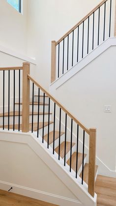 a white staircase with black railing and wood handrails