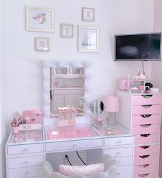 a white desk topped with a pink vanity and lots of drawers next to a tv