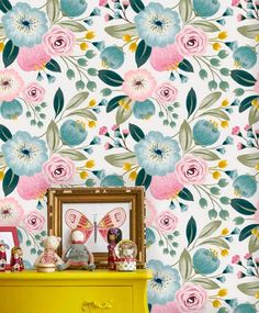 a yellow dresser sitting in front of a wallpaper covered in pink and blue flowers