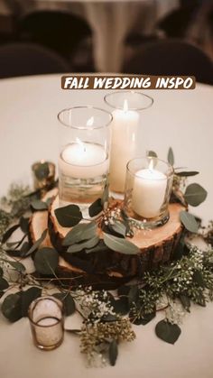 candles and greenery sit on top of a wood slice at a wedding reception table