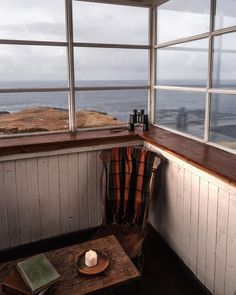 a table with a candle on it in front of a window looking out at the ocean