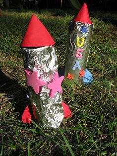 two tin foil rockets sitting in the grass