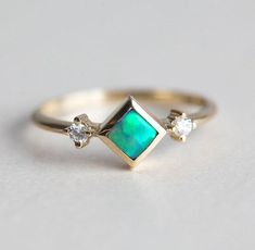 A stunning one of a kind genuine square Australian black opal and round diamond ring with beautiful interchangeable green and blue tones. Perfect as a modern and unique engagement, wedding or anniversary princess ring. A three stone ring, available in 14k yellow gold as seen online and ready for shipping in just a few days after purchase. Please select the ring size from the drop-down menu. If you have any questions, please send us a message. If you would prefer other gemstones instead of diamon Fine Jewelry Three Stone Opal Ring, Elegant Three Stone Opal Promise Ring, Fine Jewelry Green Opal Ring, Opal Three-stone Ring For Anniversary, Green Opal Ring For Anniversary, Anniversary Three Stone Opal Ring, Anniversary Green Opal Ring, Opal Diamond Engagement Ring, Engagement Ring Square