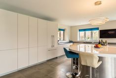 a kitchen with an island and bar stools next to the counter top in front of it