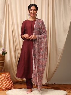 This maroon kurta set for women is a stylish and comfortable option for any occasion. The solid, panelled design is crafted from a silk blend fabric, giving it a luxurious feel. The straight shape and round neck with three-quarter sleeves add to the elegant look. The trousers feature an elasticated waistband for a perf Traditional Drape Pant Set For Eid, Unstitched Cotton Silk Suit With Cutdana, Diwali Unstitched Slub Silk Suit, Chanderi Long Sleeve Pant Set, Cotton Silk Palazzo Set For Navratri, Silk Churidar With Straight Kurta, Elegant Cotton Silk Churidar, Elegant Cotton Churidar With Cutdana, Chanderi Pant Set For Diwali